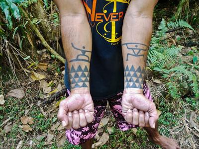 Tepaiaha shows off his tattoos - a surfer and a kayaker (with paddle)