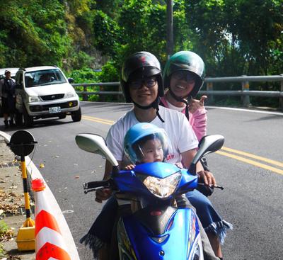 A rockfall caused a delay on the route to Liyu, so we had some time to snap photos. This family, like so many others, was fascinated by our bike trailer setup. (We didn't see any other bike trailers in Taiwan, except one that was available for rent in the Giant store in Hualien). People kept coming by to check it out, inspect the hitch, wave at Adam and sometimes take pictures. <br/> We did see small children riding their parents' scooters (standing up in the front) all the time. It's entirely normal to them. Of course Adam really wanted to ride in a scooter, but no dice.