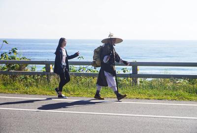 I have to assume this man is a pilgrim or spiritual guide of some kind, because the edge of the highway is an odd place for a nature hike, and also because he was followed by a handful of people who did not look like they expected to go on a hike that day.